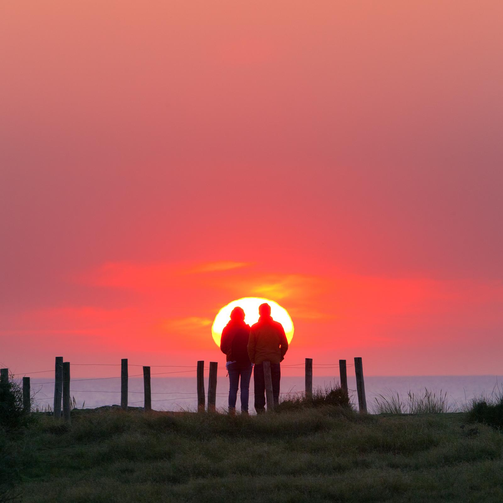 Couple au coucher du soleil face à la mer