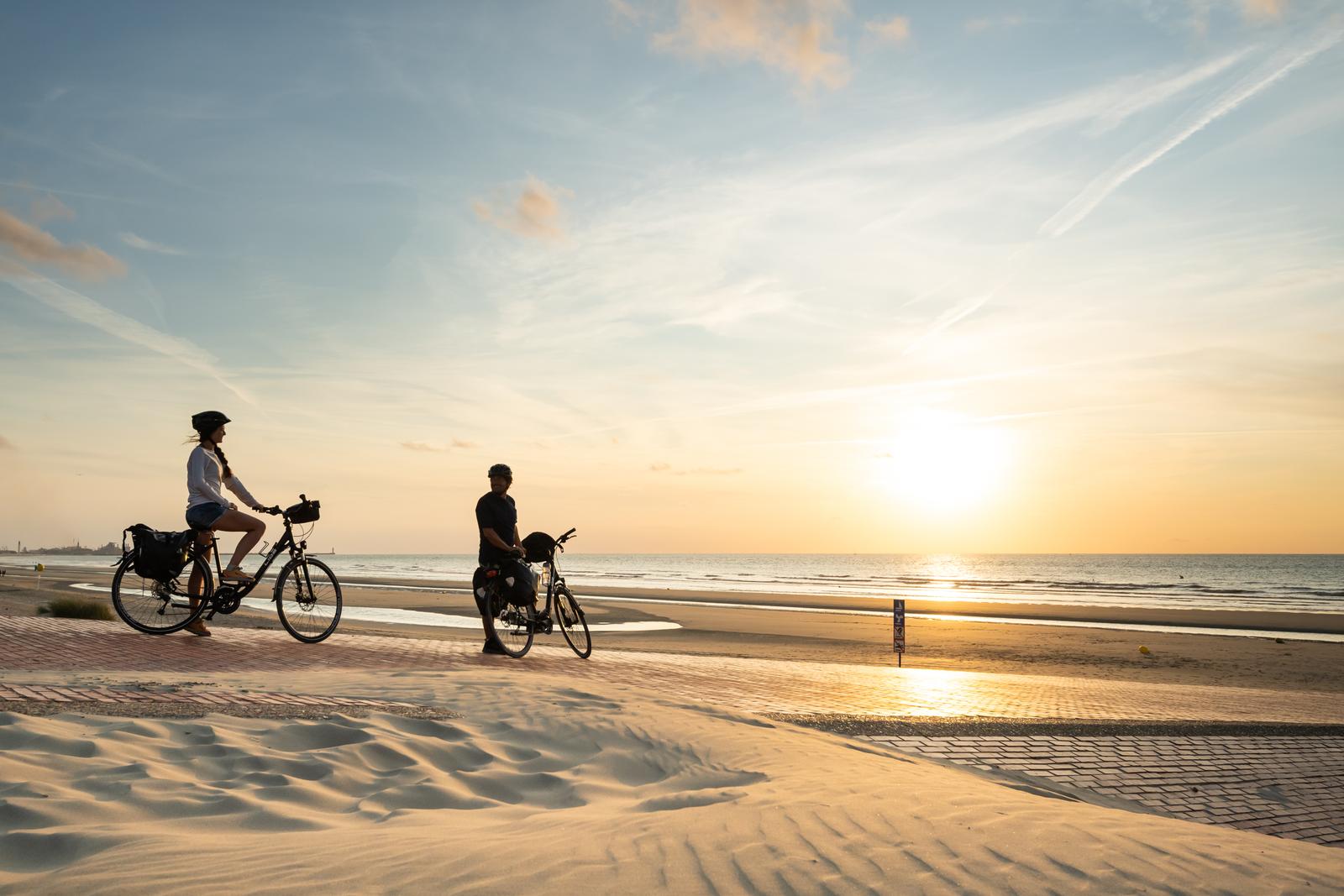 Leffrinckoucke : couple à vélo sur la plage au coucher du soleil